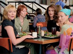 three women sitting at a table with plates of food and drinks in front of them