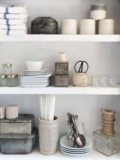 the shelves are filled with dishes, cups and utensils