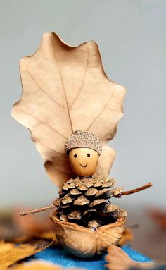 a small wooden figurine sitting on top of a pine cone