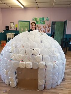 a woman standing in front of an igloose made out of plastic bottles