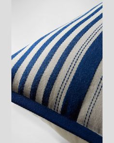 a blue and white striped pillow on a white surface