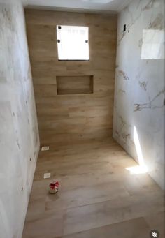 an empty bathroom with wooden floors and white marble walls, in the middle of being remodeled