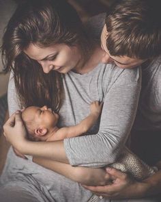 a man and woman holding a baby in their arms