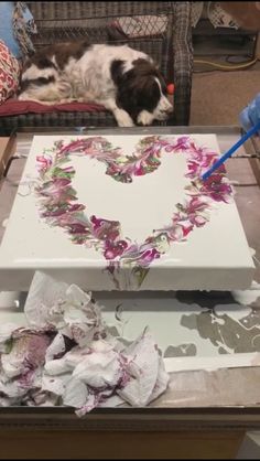 a dog laying on top of a table next to a piece of paper with a heart drawn on it