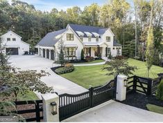 a large white house in the middle of a lush green yard with trees and bushes