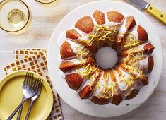 a bundt cake with lemon drizzled on top, surrounded by yellow plates and utensils