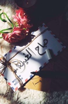 an envelope with the word love written on it next to flowers and a pair of scissors