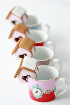 four cups with marshmallows in them are lined up on a white surface