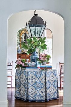 a blue and white table cloth with flowers on it in front of a lantern light