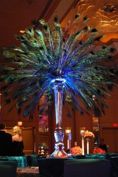 a tall vase filled with lots of blue and green feathers on top of a table