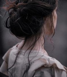 the back of a woman's head with her hair in a low bun, looking down