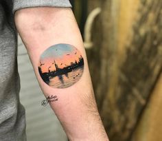 a man with a tattoo on his arm that has an image of a city in the background