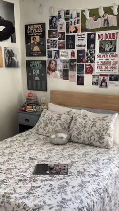 a bed sitting in a bedroom next to a wall with pictures on it and a book laying on top of the bed