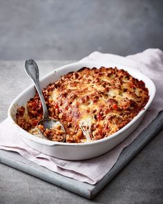 a casserole dish with meat and cheese in it on a white napkin next to a fork