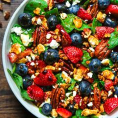 a bowl filled with berries, nuts and blueberries on top of a wooden table