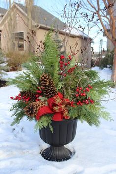 a potted plant in the snow with pine cones, berries and evergreens on it