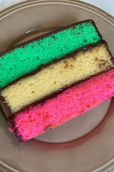 a piece of cake on a plate with pink, green and yellow frosting in the middle