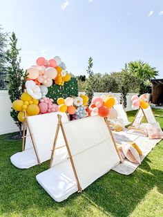 an outdoor party with balloons and decorations on the grass in front of a white fence