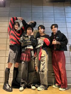 four young men standing next to each other in front of a wall with tiles on it