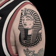 an egyptian tattoo on the back of a man's arm and shoulder, with a stylized image of a woman