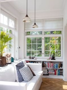 a living room filled with white furniture and lots of window sill mounted bookshelves