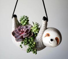 a slotty planter with succulents and plants hanging from it's sides