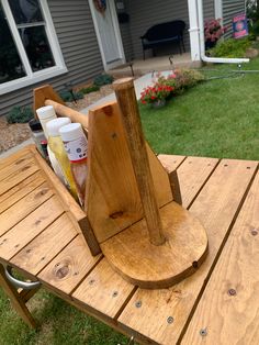 a wooden picnic table with bottles and cups on it in front of a house outside