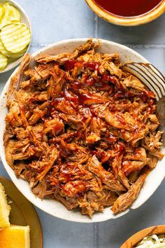 pulled pork with bbq sauce in a white bowl next to sliced apples and coleslaw