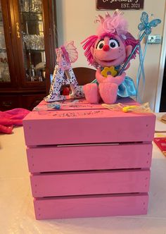 a pink toy chest sitting on top of a table next to a stuffed animal and letter