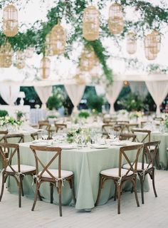 the tables are set up for an outdoor wedding reception with chandeliers hanging from the ceiling