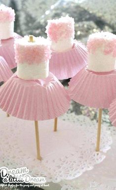 some pink cupcakes are sitting on sticks