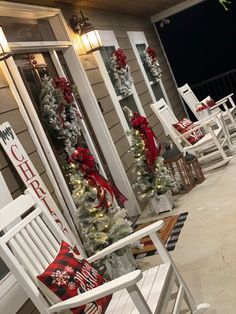 white rocking chairs with christmas decorations on the front and side of a house at night