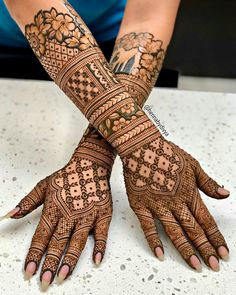 two hands with henna tattoos on them, one is showing the intricate design and the other has flowers