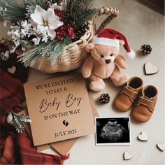 a teddy bear sitting next to a baby's first christmas card and booties