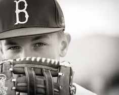 a young boy wearing a baseball glove with the letter b on it's side