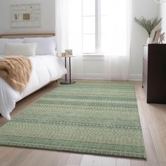 a bed room with a neatly made bed and a green rug on the wooden floor