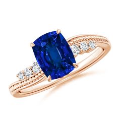 an oval blue sapphire and diamond ring with two side stones on the band, set in 18k rose gold