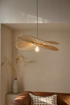 a living room with a brown couch and some lights hanging from the ceiling above it