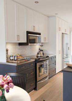 a modern kitchen with stainless steel appliances and white cabinets, along with wood flooring