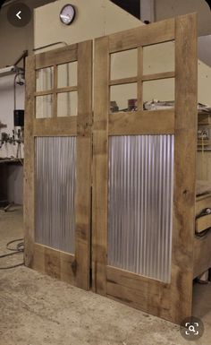 two wooden doors with glass panels in a workshop area, one open and the other closed