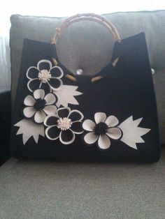 a black bag with white flowers on the front and bottom is sitting on a couch