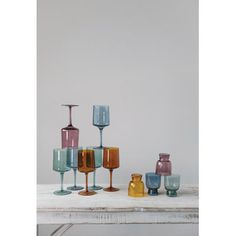 several different colored wine glasses sitting on top of a white table next to each other