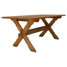 a wooden table with two crossed legs and a cross design on the top, against a white background