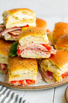 several sandwiches stacked on top of each other with meat and cheese in the middle, sitting on a plate