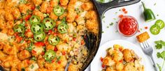 a skillet filled with tater tots and vegetables next to a plate of ketchup