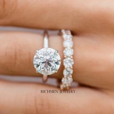 a woman's hand with two engagement rings on it and the ring has a large diamond