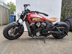 a red and black motorcycle parked in front of a white building on a brick sidewalk