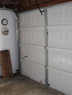 a garage with a clock on the wall next to two white garage doors that are closed