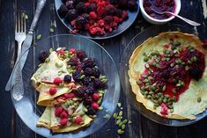 three plates with desserts on them and silverware next to one plate filled with fruit