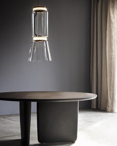 a table with a light hanging from it's side in front of a window